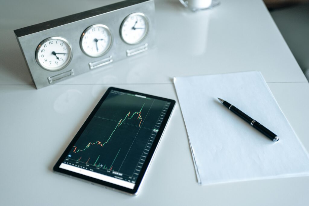 pexels photo 5833804 5833804 Tablet displaying stock chart on a minimal white workspace with clock and pen.