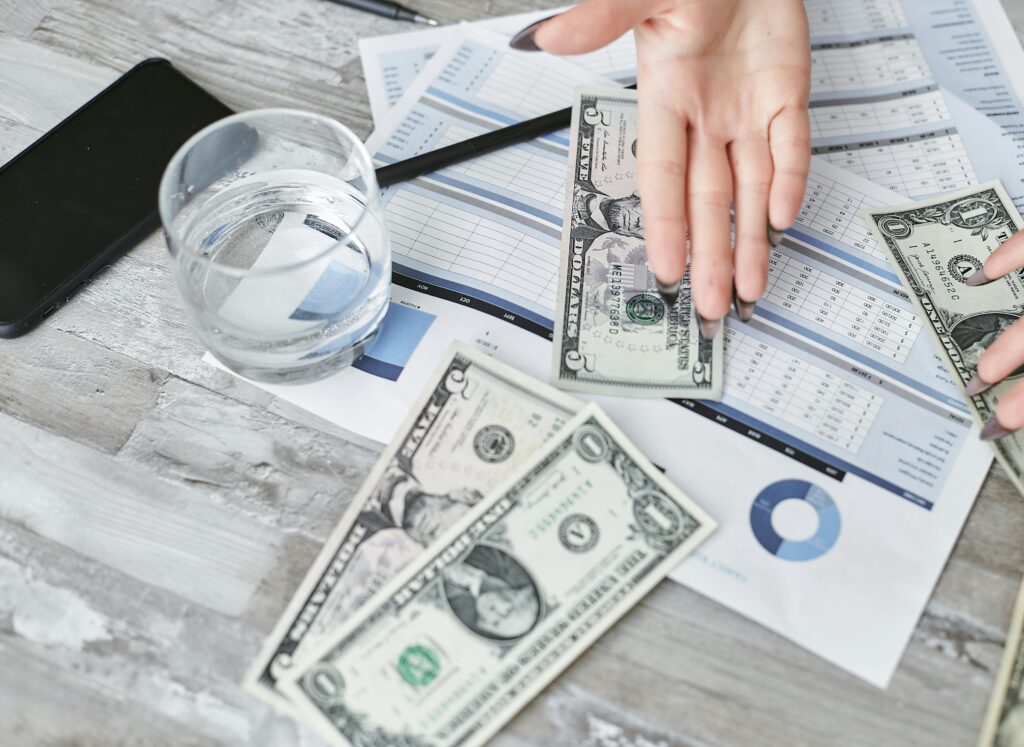 pexels photo 7735785 7735785 A top view of financial documents with dollar bills and a glass of water, emphasizing budgeting.